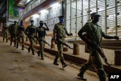 FILE - Ugandan police officers and members of Local Defence Units, a paramilitary force composed of civilians, patrol during the coronavirus lockdown after the 7 p.m. curfew in Kampala, Uganda, April, 29, 2020.