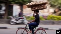 FILE - An Egyptian balances a basket of bread, in Cairo, Dec. 8, 2016.