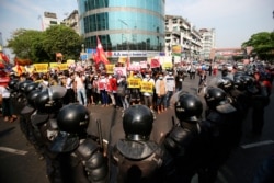 Pengunjuk rasa anti-kudeta berhadapan dengan barisan polisi anti-huru hara di Yangon, Myanmar, Jumat, 19 Februari 2021. (Foto: AP)