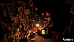FILE - A woman cooks dinner by candlelight in her home in Dala township, outside Yangon, Myanmar.