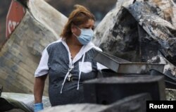 Maria Arevalo searches for items to salvage in the remains of her burned home in Phoenix, Ore., Sept. 22, 2020.