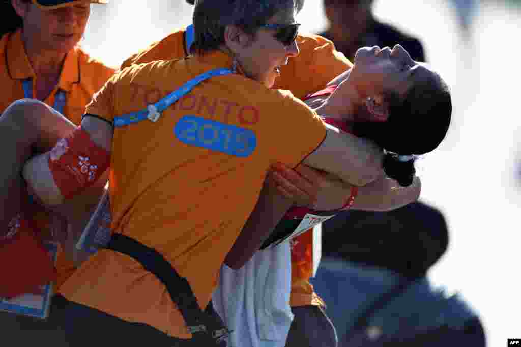 Maria Gonzalez of Mexico is assisted when she collapsed after crossing the finish line in the women&#39;s 20km Walk at the 2015 Pan American Games in Toronto, Canada. Gonzalez won with a mark of 1:29:24.