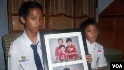 Reykhan dan Fikri Suryaman membawa foto kedua orangtua mereka, Erik Suryaman dan Neneng Nurjuwita Wati dari Cimahi, Jawa Barat, yang meninggal akibat tragedi di Mina, Arab Saudi. (VOA/R. Teja Wulan)