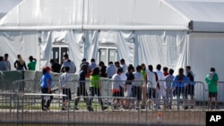 FILE - Children, some separated from migrant families at the U.S.-Mexico border, line up to enter a tent at a shelter for migrant children in Homestead, Florida, Feb. 19, 2019.