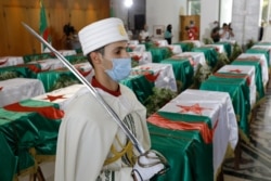 FILE - A soldier guards the remains of 24 Algerians at the Moufdi-Zakaria culture palace in Algiers, July, 3, 2020. After decades in a French museum, the skulls of the 24, decapitated for resisting French colonial forces, were formally repatriated.