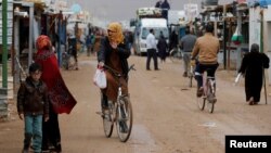 FILE - Syrian refugees ride bicycles during rainy weather at the Zaatari refugee camp in the Jordanian city of Mafraq, near the border with Syria, Dec. 18, 2016.