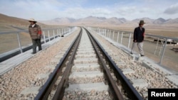 FILE - Two workers walk along the Qinghai-Tibet Railway as they check the railway track, in Dangxiong county of the Tibet Autonomous Region. (Reuters)