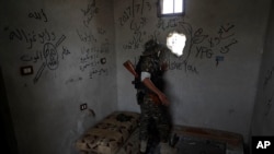 A U.S.-backed Syrian Democratic Forces fighter looks through a hole from his position into an Islamic State controlled street on the front line on the western side of Raqqa, Syria, July 17, 2017.