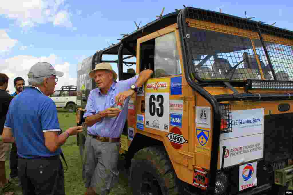 People chat at Rhino Charge as cars are inspected in Narok county, Kenya, May 29, 2016. Teams are allowed up to six people per vehicle, usually made up of a driver, a navigator and up to four runners. (J. Craig/VOA)