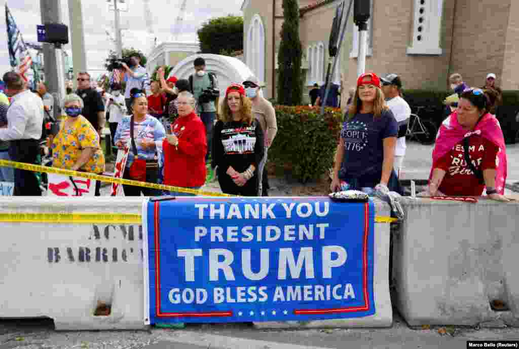 Pendukung Presiden AS Donald Trump berdiri di dekat jalan untuk menyambut kedatangan Trump di West Palm Beach, Florida, AS, Rabu 20 Januari 2021. Trump meninggalkan Washington DC menuju Florida Rabu pagi dan tidak menghadiri acara pelantikan Presiden Joe Biden. (Foto: REUTERS / Marco Bello)