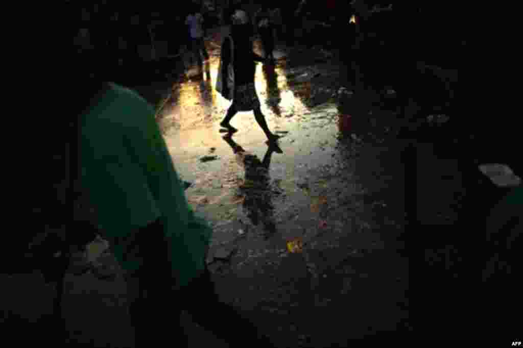 A woman crosses a street covered with dirty water in Port-au-Prince dowtown, Haiti,Thursday, Nov. 11, 2010. (AP Photo/Emilio Morenatti)