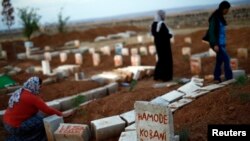 Dayikeke Kurd li ser gora şervanên YPG de dua dike Cotmeh 15, 2014.
