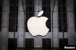 FILE - An Apple logo hangs above the entrance to the Apple Store on Fifth Avenue in the Manhattan borough of New York City,  July 21, 2015.