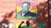 A supporter of Zimbabwean President Robert Mugabe chants the party's slogan while standing underndeath a portrait of Mugabe in Harare, Sunday, Feb. 21, 2016. Zimbabwean President Robert Mugabe turned 92 on Sunday making him the worlds oldest serving President. Mugabe.On Friday Mugabe delivered a televised speech warning ruling ZANU PF rival factions to end succession fights he described as "very ugly" ahead of his birthday party celebrations to be held in south- eastern town of Masvingo on Saturday.(AP Photo/Tsvangirayi Mukwazhi)