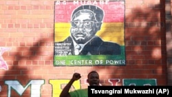 A supporter of Zimbabwean President Robert Mugabe chants the party's slogan while standing underndeath a portrait of Mugabe in Harare, Sunday, Feb. 21, 2016. Zimbabwean President Robert Mugabe turned 92 on Sunday making him the worlds oldest serving President. Mugabe.On Friday Mugabe delivered a televised speech warning ruling ZANU PF rival factions to end succession fights he described as "very ugly" ahead of his birthday party celebrations to be held in south- eastern town of Masvingo on Saturday.(AP Photo/Tsvangirayi Mukwazhi)