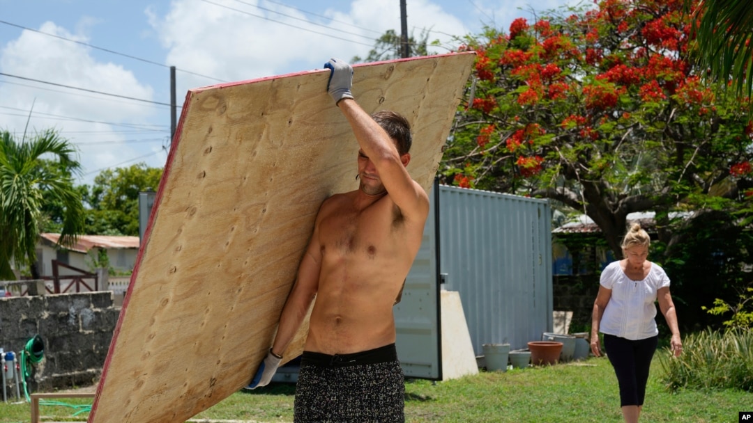 Un vecino carga un tablón de madera para cubrir las ventanas de su casa en preparación para el huracán Beryl, en Bridgetown, Barbados, el 30 de junio de 2024.