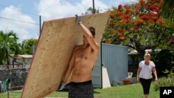 Un vecino carga un tablón de madera para cubrir las ventanas de su casa en preparación para el huracán Beryl, en Bridgetown, Barbados, el 30 de junio de 2024.