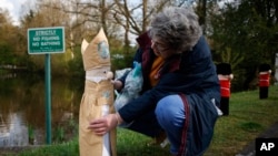 Heather Howarth of the 'Hurst Hookers' knitting group attaches a knitted figure of Britain's Archbishop of Canterbury Justin Welby to a post during a pre-coronation 'yarn bombing' in the village of Hurst, near Reading, England, April 21, 2023.