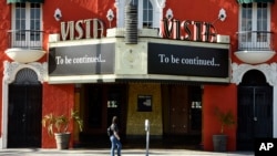 FILE - A pedestrian looks up at a "To be continued…" message on the marquee of the Vista theatre, April 21, 2020, in Los Angeles. Movie theaters remain closed as stay-at-home orders continue because of the coronavirus pandemic.