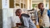 Two men review voter results posted outside a classroom used as a polling station in Beira, Mozambique, on Oct. 10, 2024, the day after Mozambique's national election. 