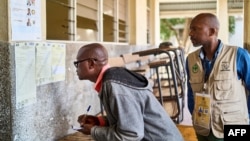 Two men review voter results posted outside a classroom used as a polling station in Beira, Mozambique, on Oct. 10, 2024, the day after Mozambique's national election. 