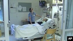 A heart patient's vital stats are checked by one of the medical staff