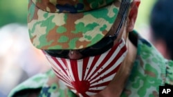 A visitor wearing a protective mask to help curb the spread of the coronavirus pays respects to the war dead at Yasukuni Shrine Saturday, Aug. 15, 2020, in Tokyo. Japan marked the 75th anniversary of the end of World War II. (AP Photo/Eugene Hoshiko)