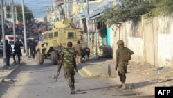 FILE - African Union Mission to Somalia (AMISOM) soldiers carry the wreckage of a vehicle at the scene of suicide bombing that targeted AMISOM forces in Mogadishu, Somalia, on Nov. 11, 2021.