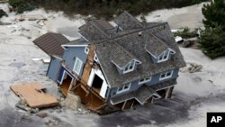 FILE - This Oct. 31, 2012 file aerial photo shows a collapsed house along the central Jersey Shore coast. Polling shows that a clear majority of mayors are prepared to confront President Donald Trump's administration over climate change.