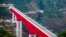 In this photo released by Xinhua News Agency, an electric multiple unit (EMU) train of the China-Laos Railway crosses a major bridge over the Yuanjiang River in southwestern China's Yunnan Province, Dec. 3, 2021. 