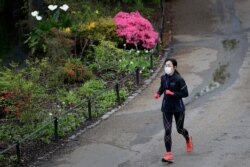 A jogger wears a protective face mask to protect against coronavirus, runs through St James's Park as the country continues its lockdown in an attempt to control the spread of the virus, in London, April 18, 2020.