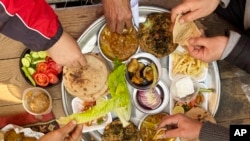 FILE - Egyptian workers eat on a truck in Cairo, Egypt, January 22, 2023. Egypt is in an economic crisis is partly caused by the yearlong grinding Russian invasion of Ukraine.