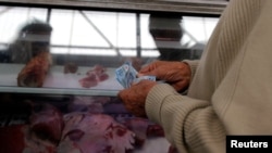 FILE - A man counts money to pay for goods at the Granada market in Mexico City, Jan. 10, 2017. 