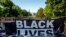The White House is visible behind a large banner that reads Black Lives Matter that hangs on a security fence at 16th and H Street, June 8, 2020, in Washington.