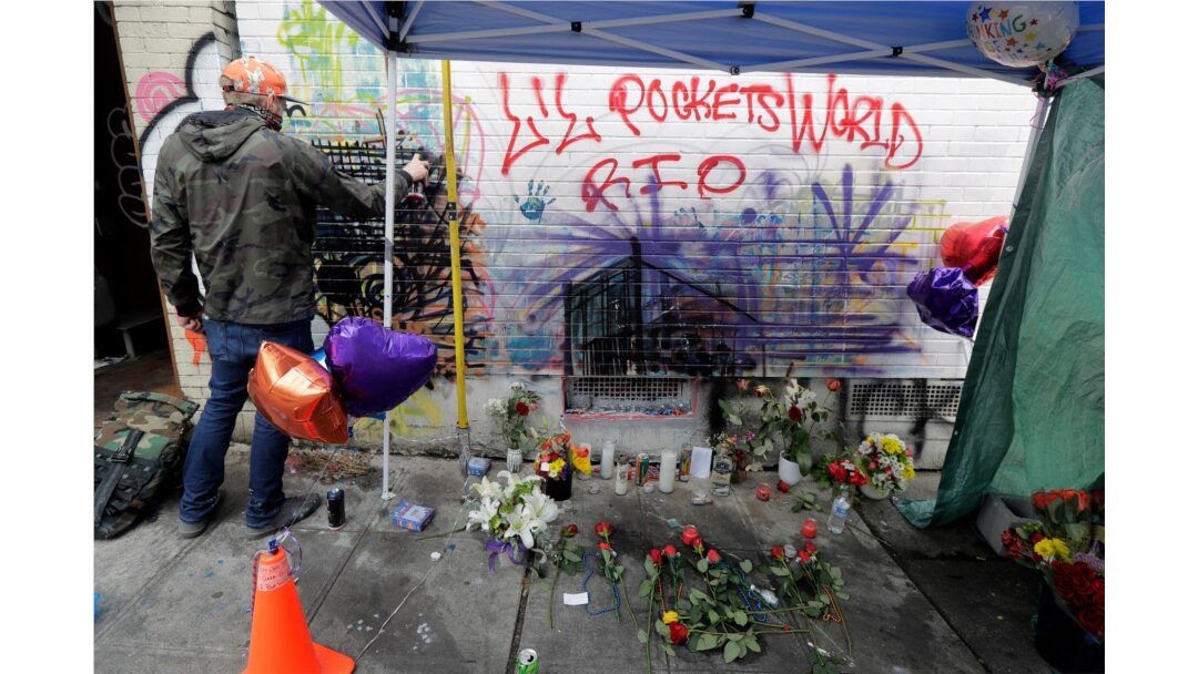 Un artista, a la izquierda, trabaja en una pieza con pintura en aerosol y tiza, el martes 30 de junio de 2020, junto a un monumento en memoria de un adolescente de 16 años que murió cerca en un tiroteo el 29 de junio de 2020 en Seattle, Washington.