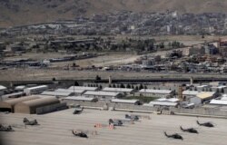 Kabul Military Airport where helicopters are parked are seen through a window of a commercial airplane, July 7, 2021.