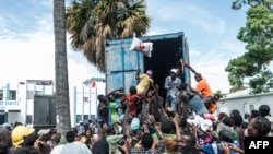 Seorang pria melemparkan sekantong beras ke kerumunan korban gempa yang berkumpul untuk pembagian makanan dan air di persimpangan "4 Chemins" di Les Cayes, Haiti, 20 Agustus 2021. (Foto: AFP)