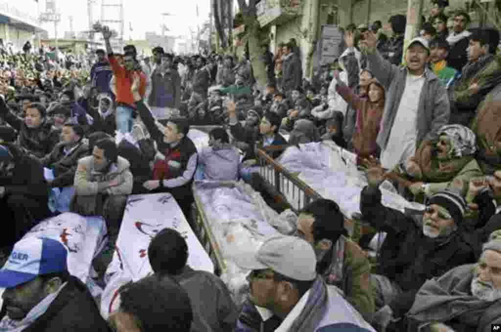 Pakistani Shiite Muslims sit next to bodies and await the burial of their relatives and friends who were killed in Thursday's deadly bombings, during a protest in Quetta, Pakistan, Saturday, Jan. 12, 2013. About 3,500 Pakistani Shiites protested in southw