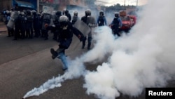 A riot policeman kicks a tear gas canister to demonstrators, during a protest against the re-election of Honduran President Juan Orlando Hernandez in Tegucigalpa, Honduras, Jan. 20, 2018.