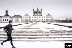 Čovjek trči pored snijegom prekrivene rezidencije danske kraljice Margrethe u Fredensborgu, 9. januara 2024. (Foto: AFP/Mads Claus Rasmussen/Ritzau Scanpix)