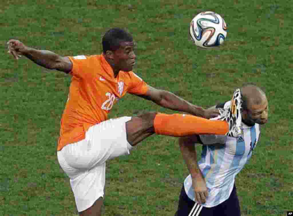 Netherlands' Georginio Wijnaldum kicks the ball as Argentina's Javier Mascherano tries a header during the World Cup semifinal soccer match between the Netherlands and Argentina at the Itaquerao Stadium in Sao Paulo Brazil, Wednesday, July 9, 2014. (AP Ph