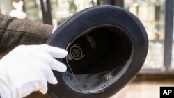 A man holds a hat with the initials of Adolf Hitler prior to an auction in Grasbrunn, Germany, Nov. 201, 2019. 