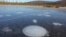 Methane bubbles up from the thawed permafrost at the bottom of the thermokarst lake through the ice at its surface. (Katey Walter Anthony/ University of Alaska Fairbanks)