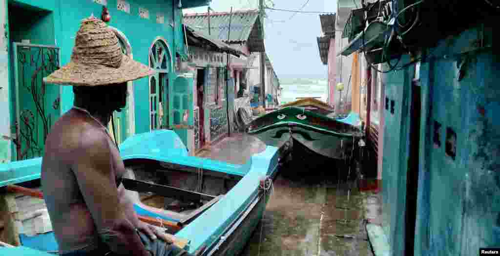 A fisherman sits on the top of a boat after pulling it back to land, as Cyclone Burevi is moving near the coast of Trincomalee, Sri Lanka.