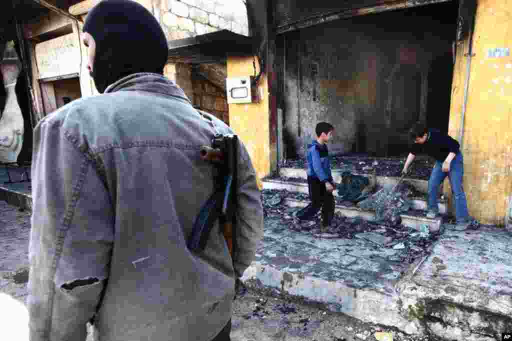 Children clean up a shop after heavy shelling by government forces near Idlib, February 28, 2012. (Reuters)