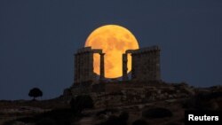 An almost full moon rises over the Temple of Poseidon in Cape Sounion, near Athens, Greece, Aug. 21, 2021.