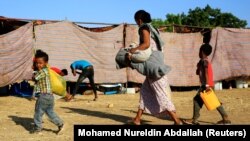 Seorang wanita Ethiopia dan anak-anaknya yang melarikan diri dari perang di wilayah Tigray, membawa barang-barang mereka saat tiba di kamp Um-Rakoba, di perbatasan Sudan-Ethiopia di negara bagian Al-Qadarif, Sudan, 19 November 2020. (Foto: REUTERS/Mohamed Nureldin Abdallah)