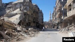 A resident walks past damaged buildings in the Damascus suburb of Zamalka, Syria, May 2, 2014. 