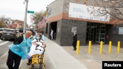 Emergency Medical Technicians move a patient while wearing personal protective equipment outside of Elmhurst Hospital during the ongoing outbreak of the coronavirus disease (COVID-19) in the Queens borough of New York, April 20, 2020.