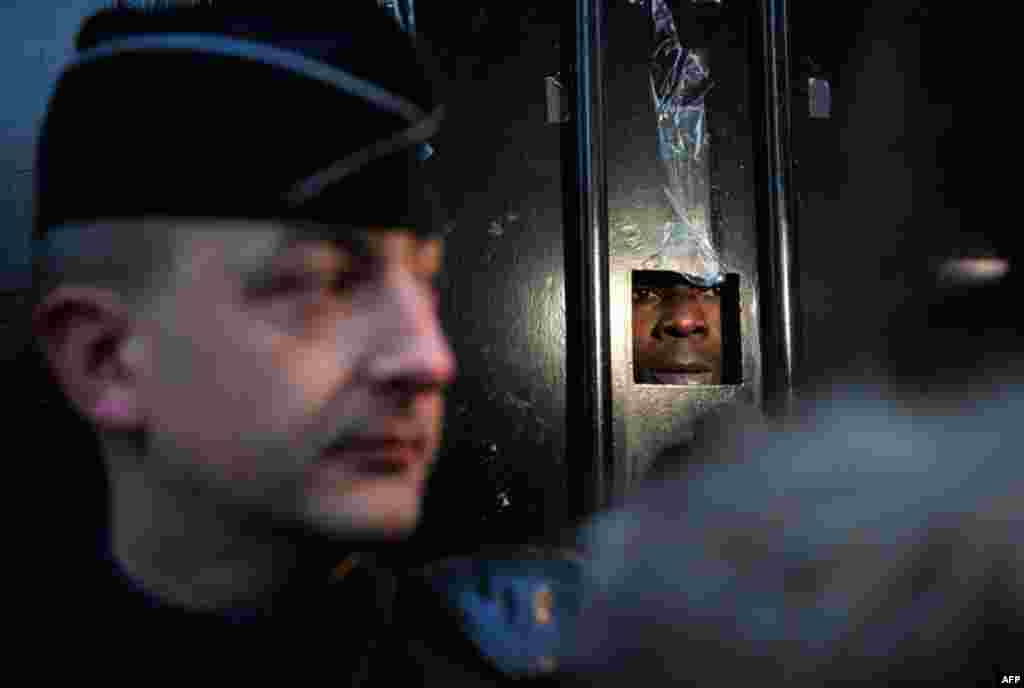 Dec. 27: A man speaks to journalists from inside the Ivory Coast embassy in Paris as police guard the entrance. (Philippe Wojazer/Reuters)